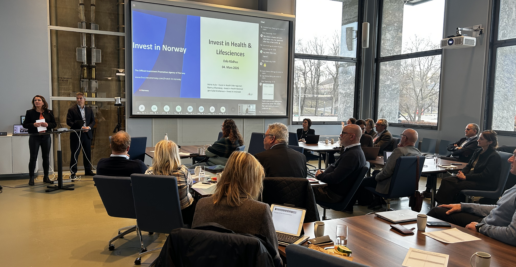 To personer står ved en skjerm, og mange mennesker ser mot skjermen