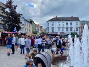 Hønefoss torg. Mange mennesker, boder og fontene.